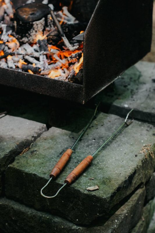 Charcoal grill with burning coals and grill tongs, ideal for outdoor BBQ enthusiasts.