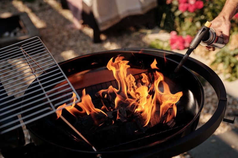 A charcoal grill ignited with flames using a torch. Perfect for outdoor barbecues.